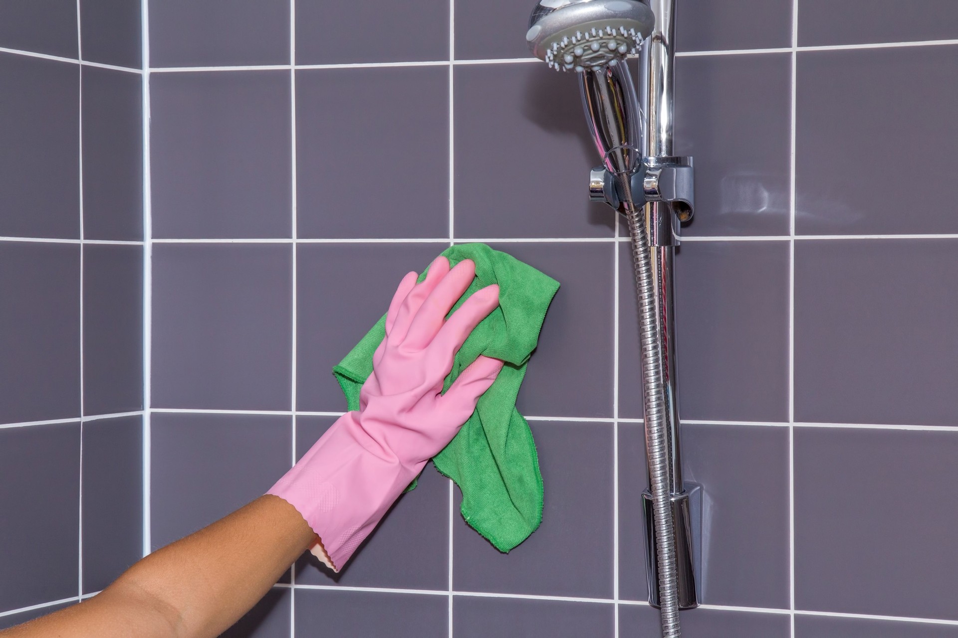 In the bathroom, shower tiles and water tap washing.
