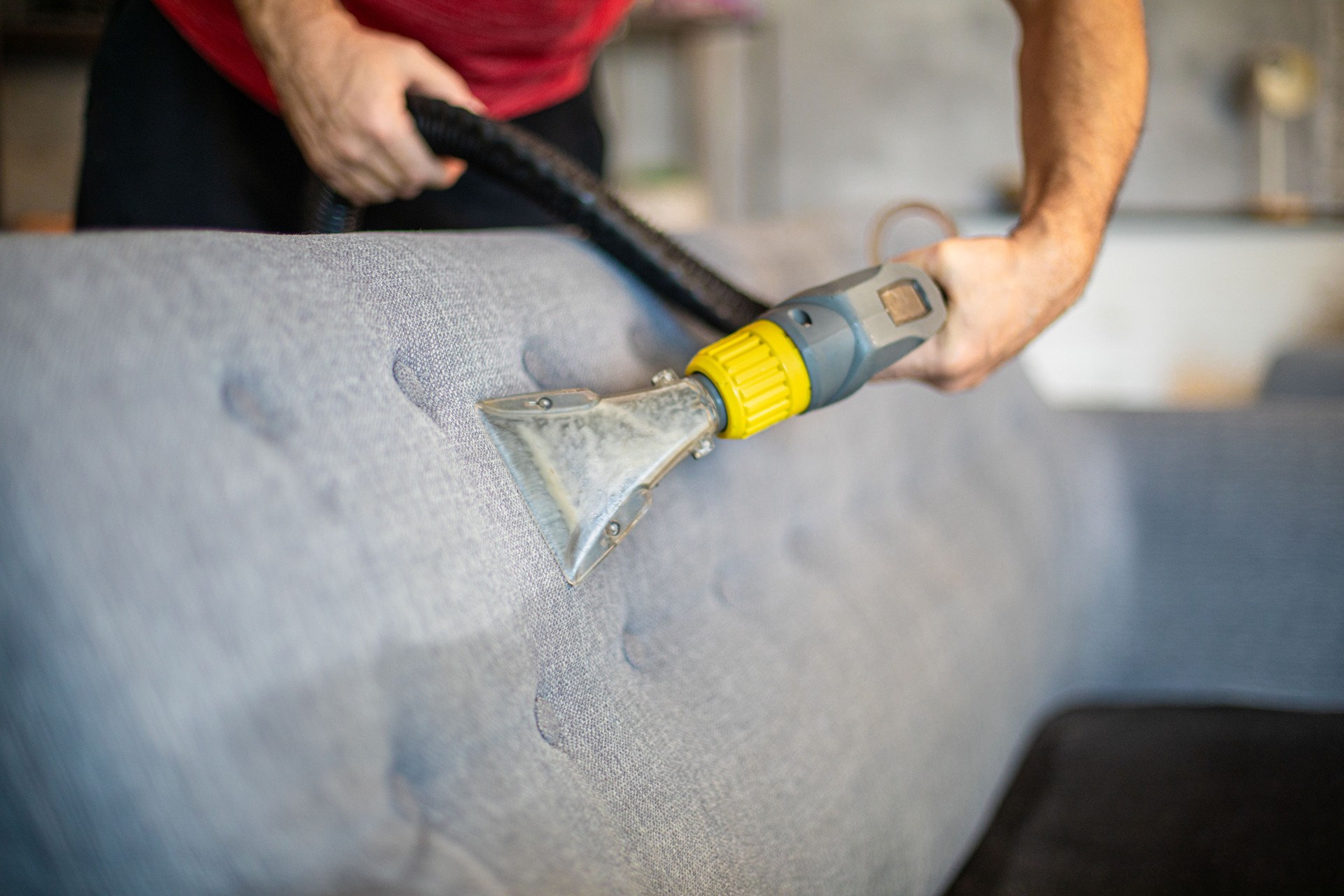 Cleaner is using extractor machine to clean the bed mattress in the house